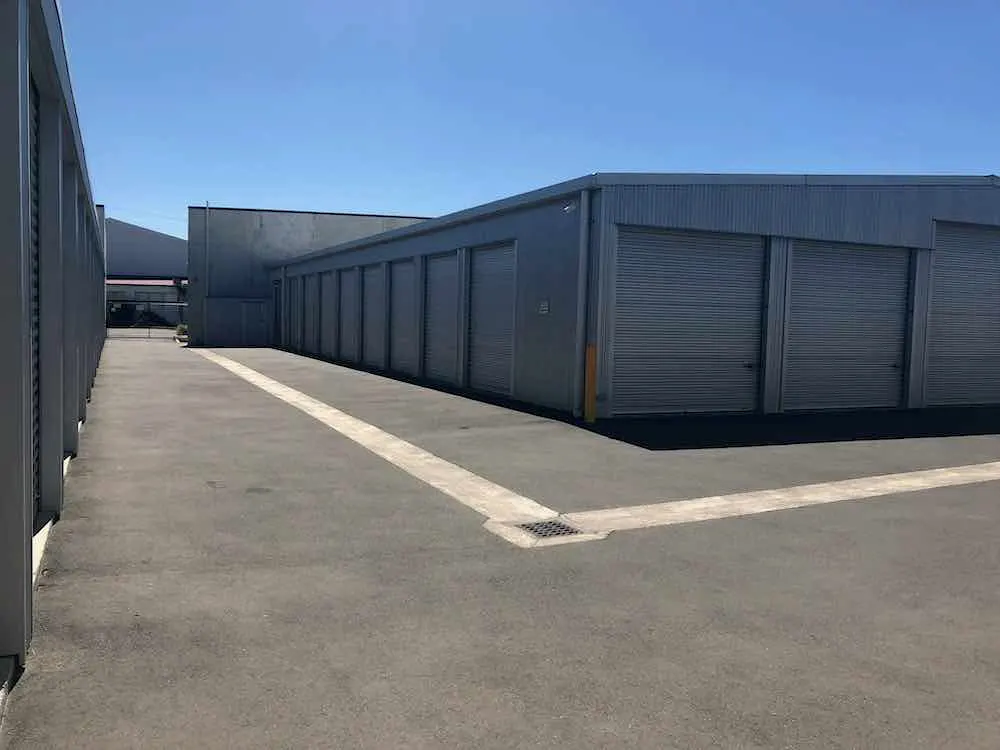 Rows of storage unit roller doors along a paved drive